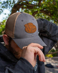 Man wearing VP Racing leather patch hat in gray and khaki, showcasing casual style and racing fan fashion in an outdoor setting.