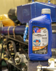 lifestyle image showing a bottle of Pro Grade 15W50 synthetic oil sitting on counter with a racing engine in the background