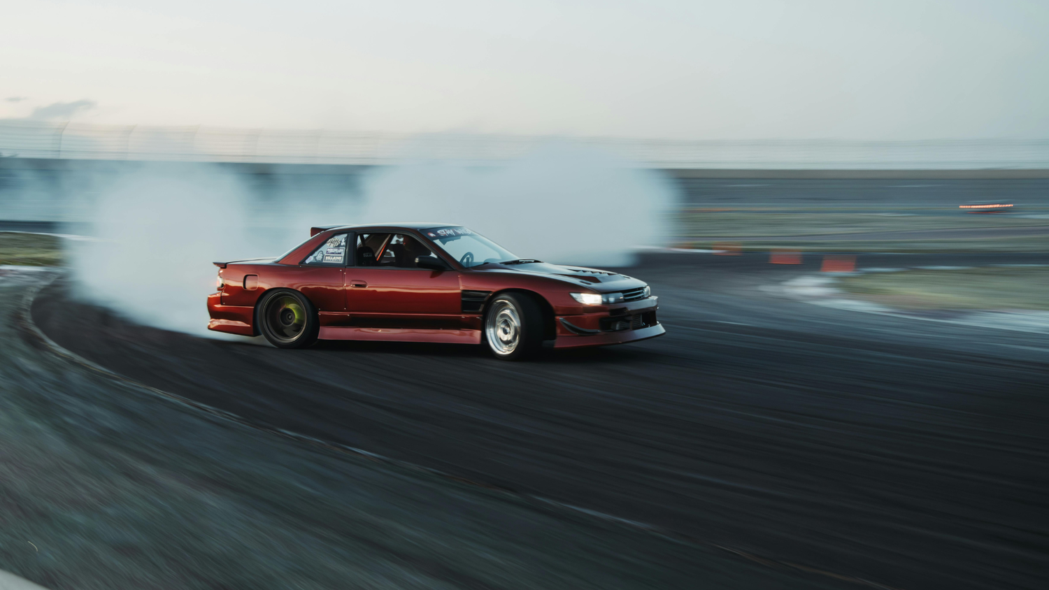 Drag racing car producing tire smoke on track