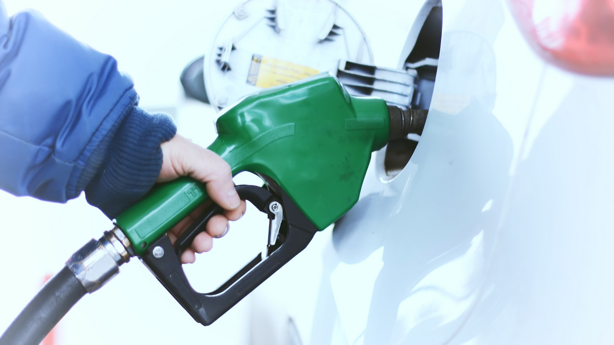 Green gasoline pump nozzle refueling a vehicle