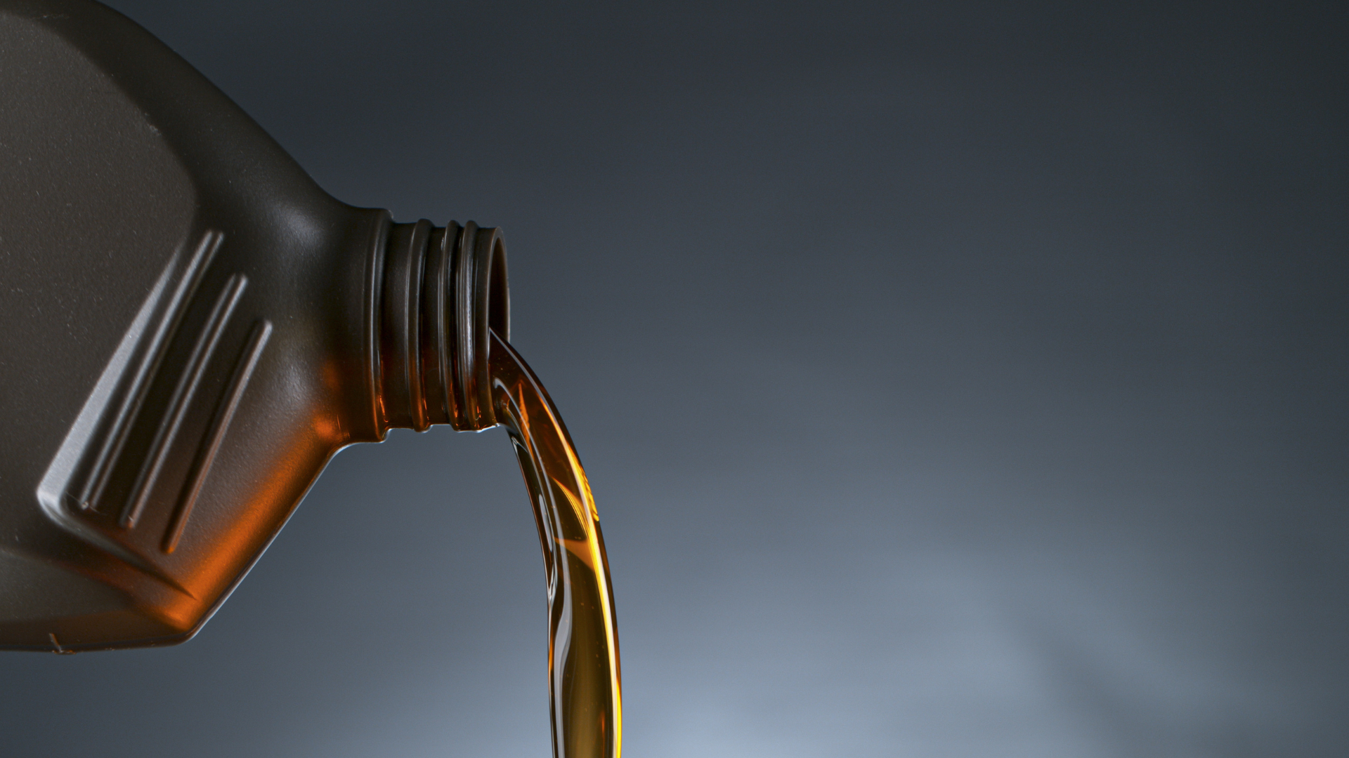 Motor oil pouring from a container into an engine