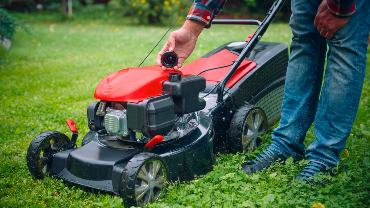 Opening a lawn mower gas cap to inspect fuel storage condition
