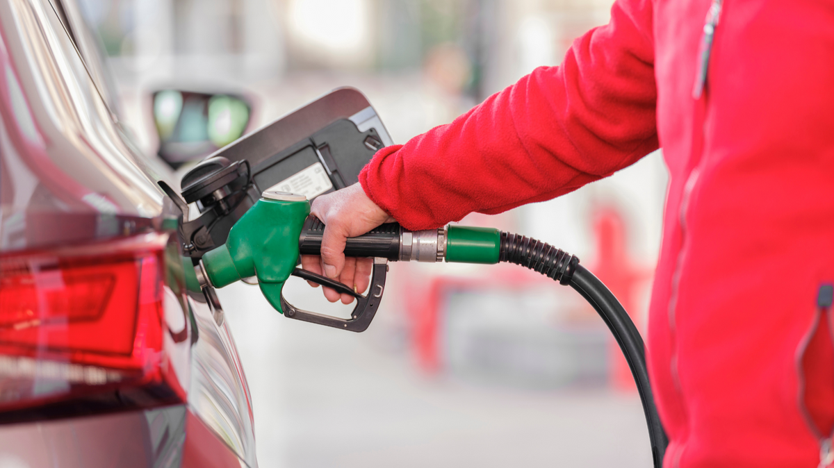 Person refueling a car with a gasoline pump