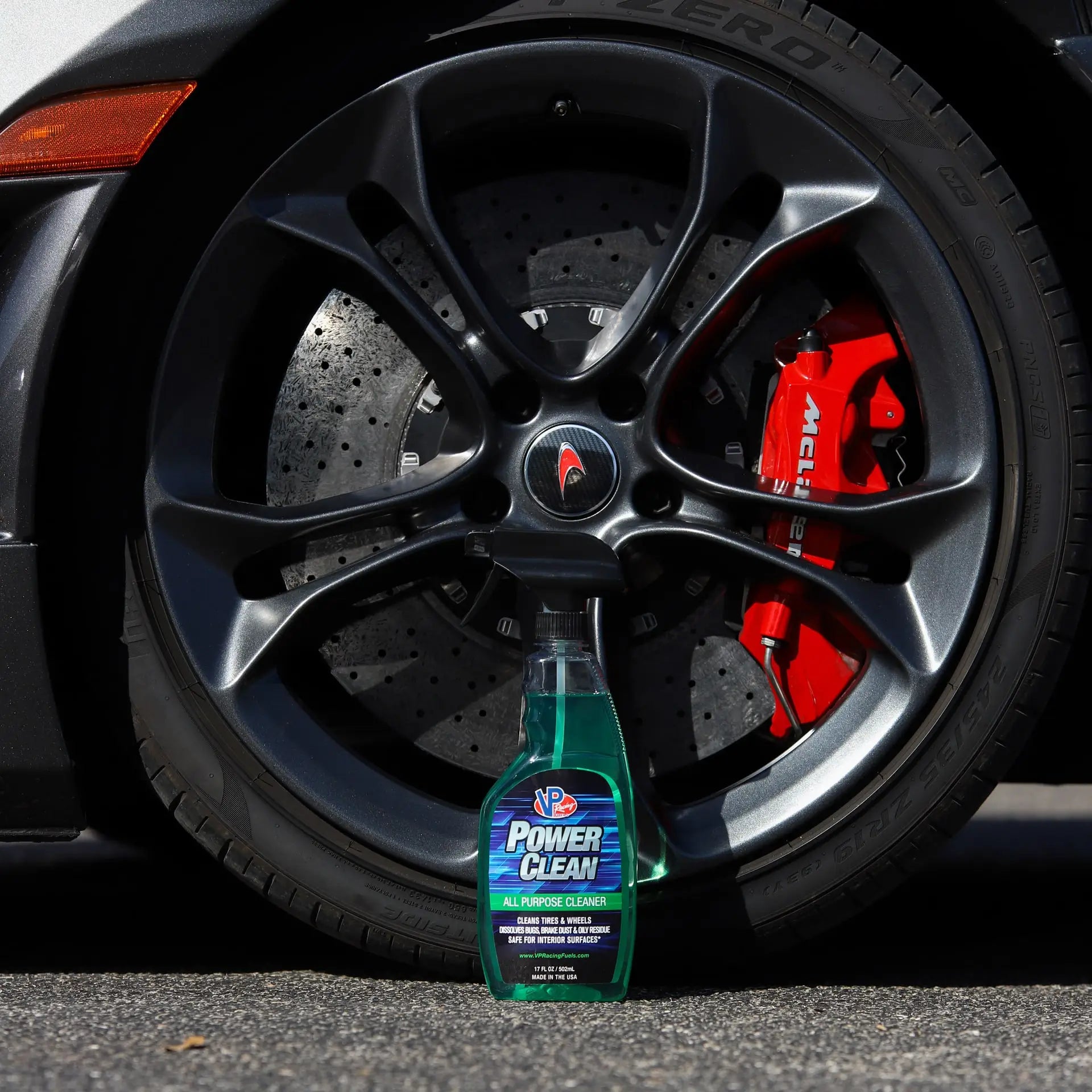 lifestyle image showing a bottle of VP Power Clean all-purpose cleaner for cars sitting on the ground in front of a wheel of a sports car