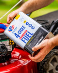 A person pouring VP Racing 4-Cycle fuel from a one-gallon container into the small engine of a red lawn mower.