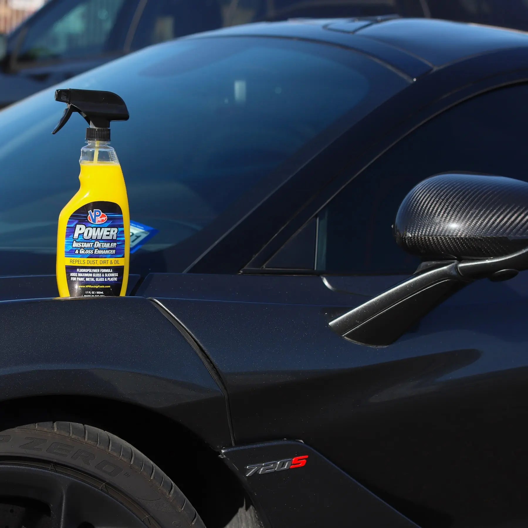 lifestyle image of a bottle of VP Racing&#39;s instant detailer spray sitting on the hood of a car near the windshield