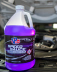 lifestyle image showing Speed Sauce Water-Methanol Injection kit fluid sitting near an engine compartment of an automobile