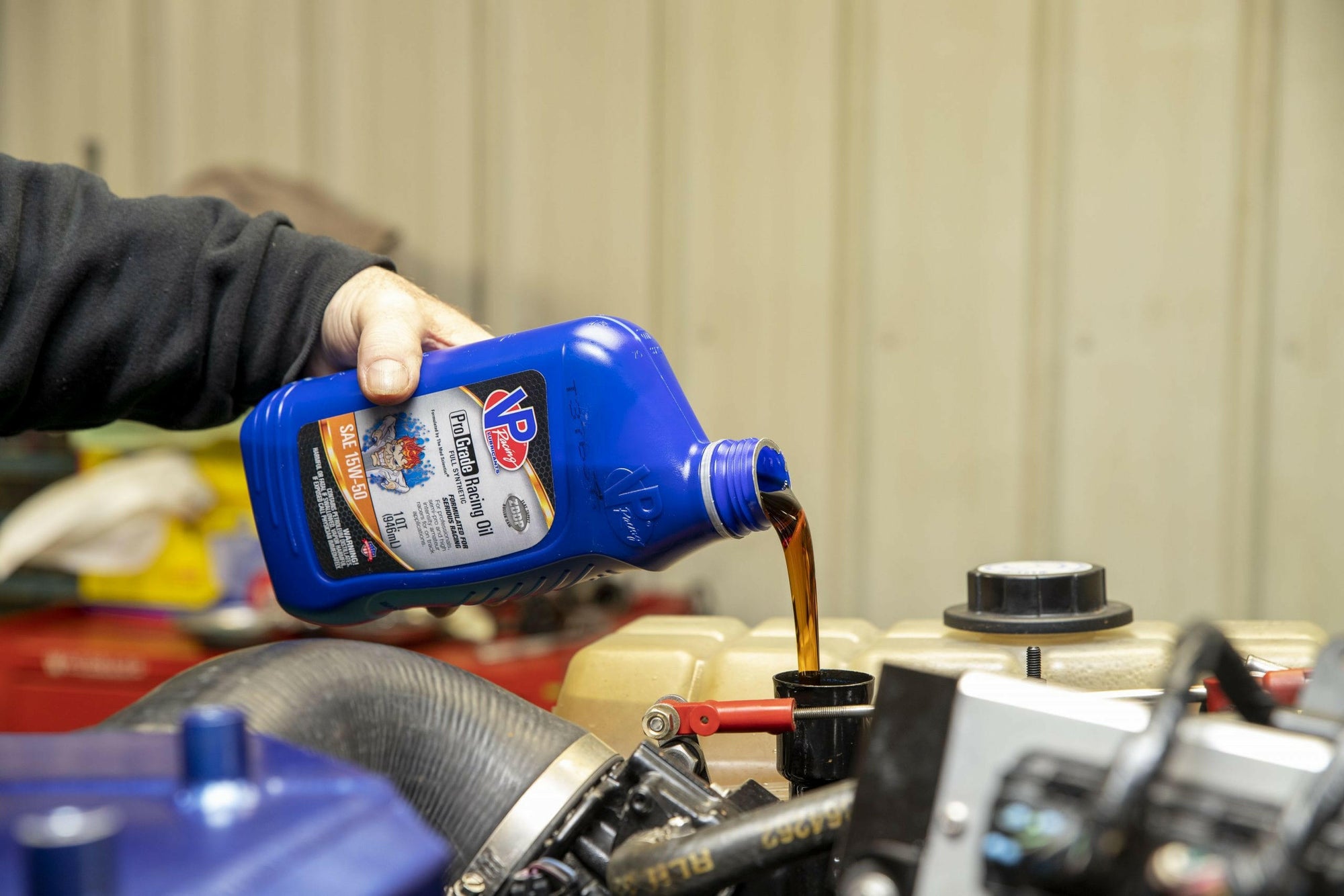 lifestyle image showing a closeup of someone pouring a quart of VP Pro Grade Engine oil into a racing engine