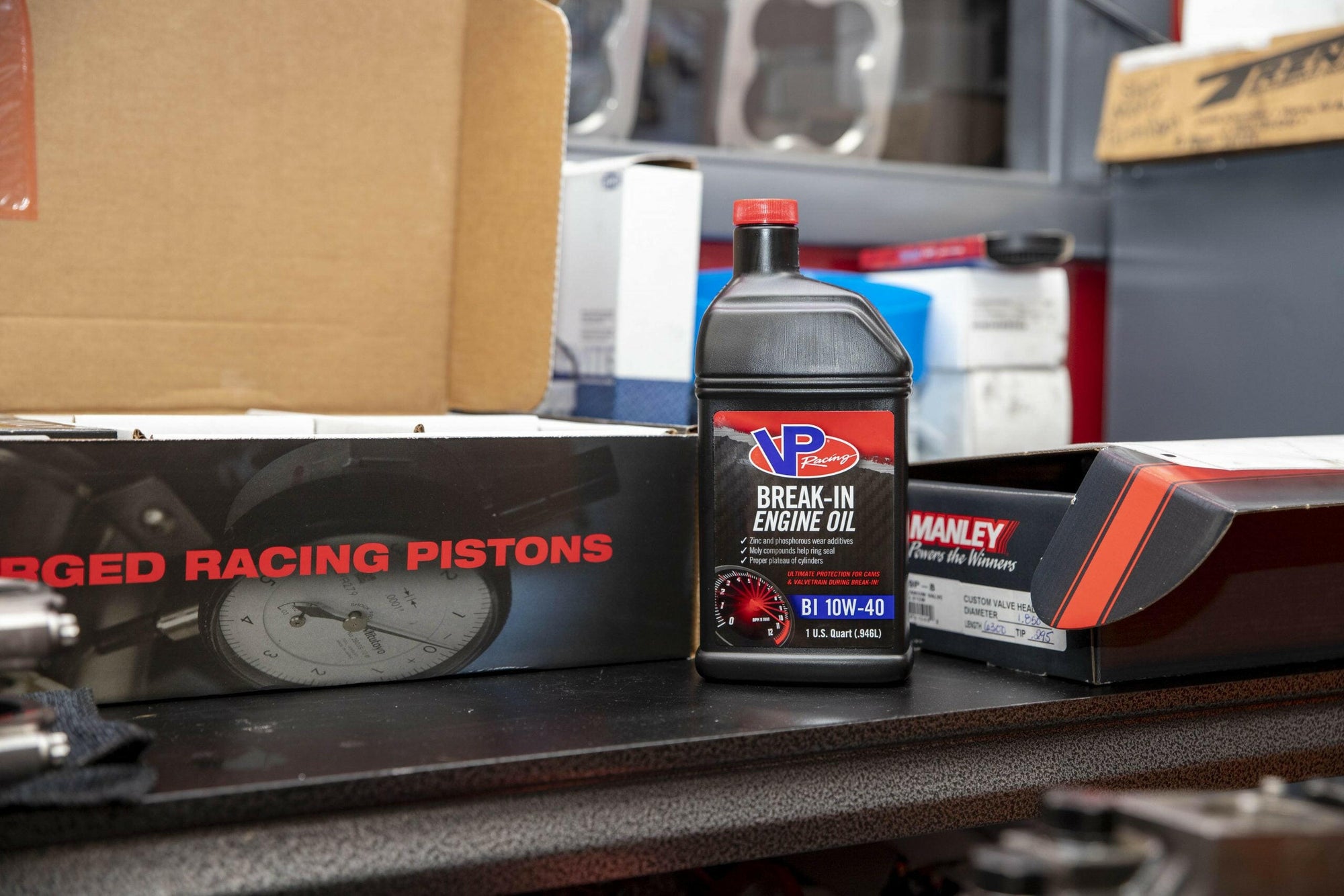 lifestyle image showing a bottle of VP engine break-in oil sitting on a counter next to a box of racing pistons