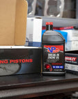 lifestyle image showing a bottle of VP engine break-in oil sitting on a counter next to a box of racing pistons