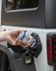 lifestyle image showing a closeup of someone pouring a bottle of VP fuel system cleaner into a gas tank of a Jeep