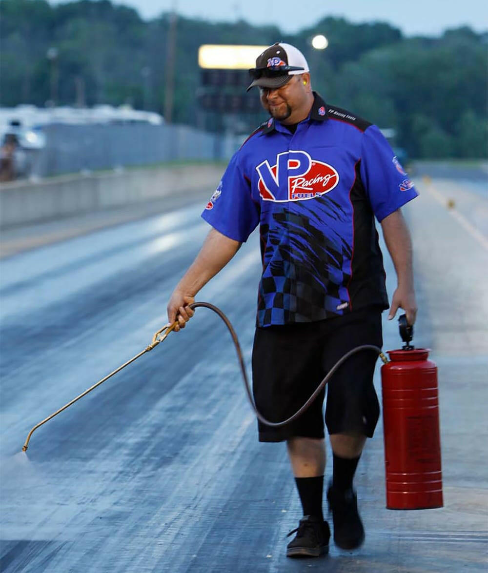 image of a man in a VP Racing shirt spraying VP Starting Line Resin on a race track