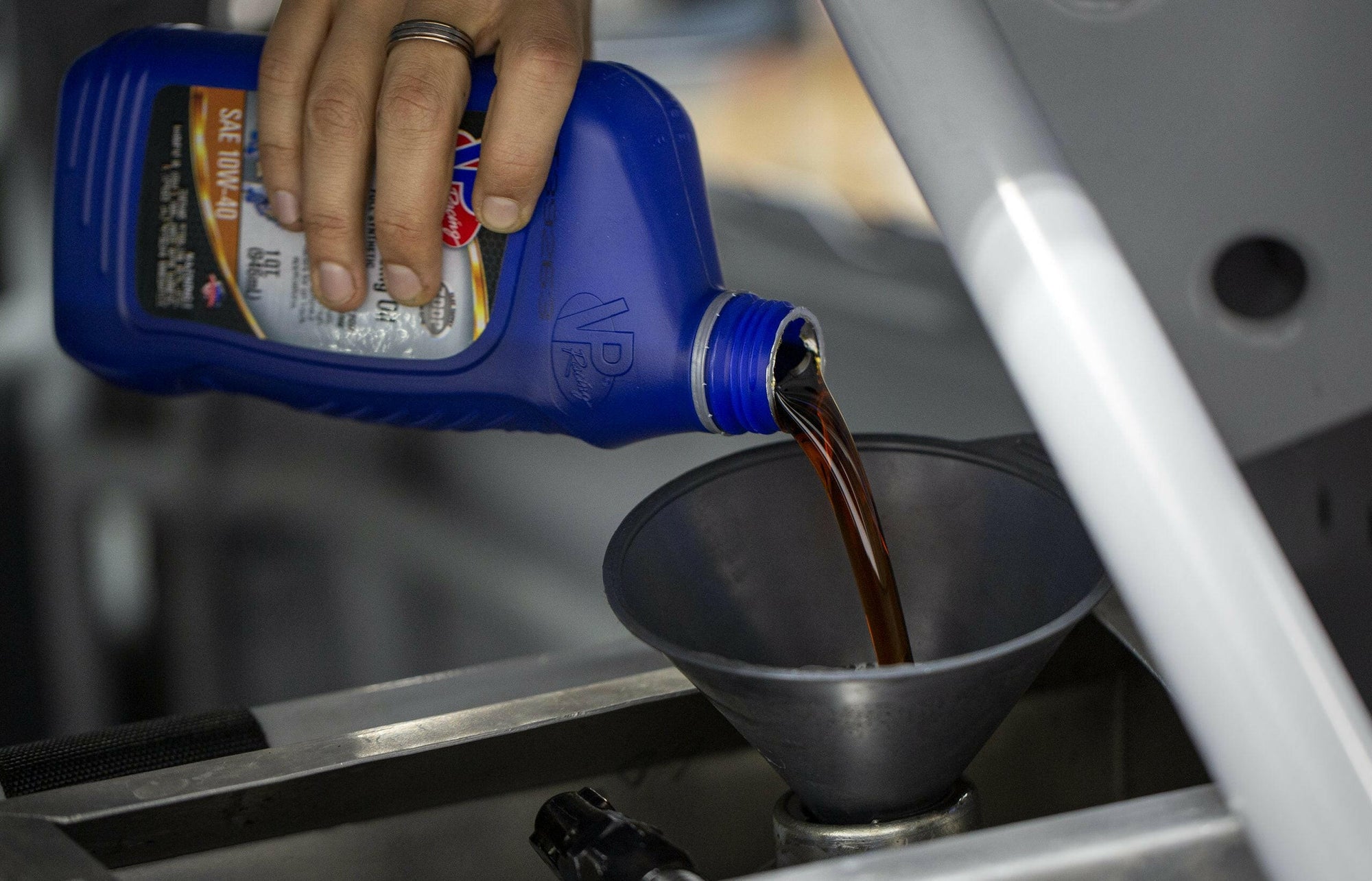 closeup of someone pouring a quart of Pro Grade 0w20 full synthetic oil into a funnel