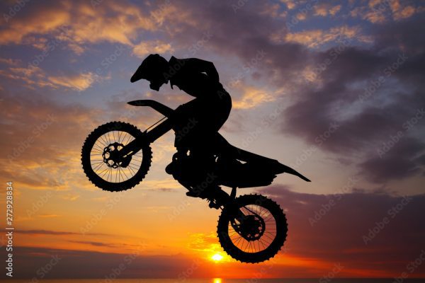 Silhouette of rider doing a wheelie on a trials motorcycle at sunset