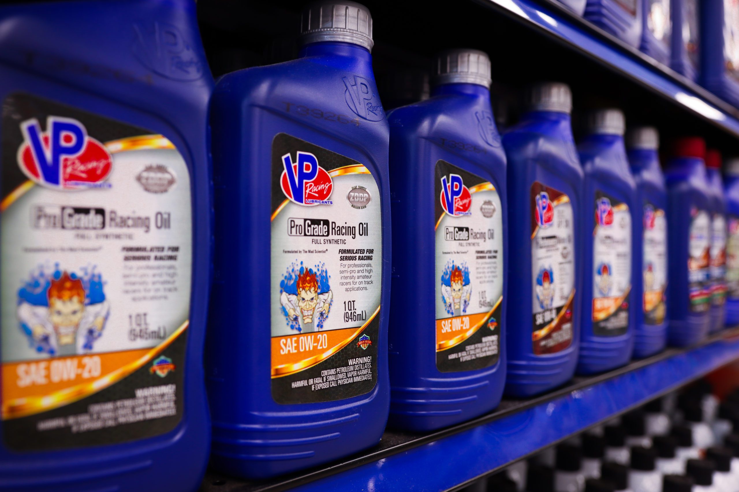 multiple quart bottles of VP Pro Grade synthetic racing engine oil pictured on a store shelf. Photo is at a slight angle going left to right