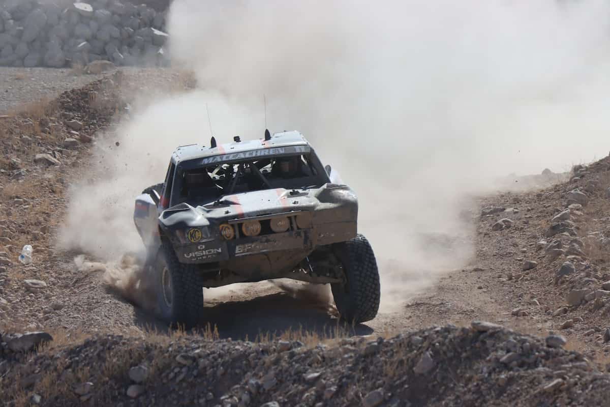 Afternoon wide shot of Rob MacCachren racing his trophy truck through the desert. The shot shows the front of his truck as he’s coming toward the camera.