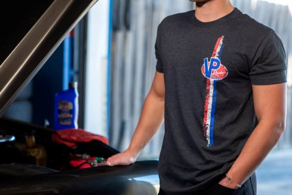 Male model wearing the VP Racing Stripes of Glory t-shirt. Black shirt with vertical red, white, and blue tire-tread looking striples down the front left side with the VP Racing logo on the left chest.