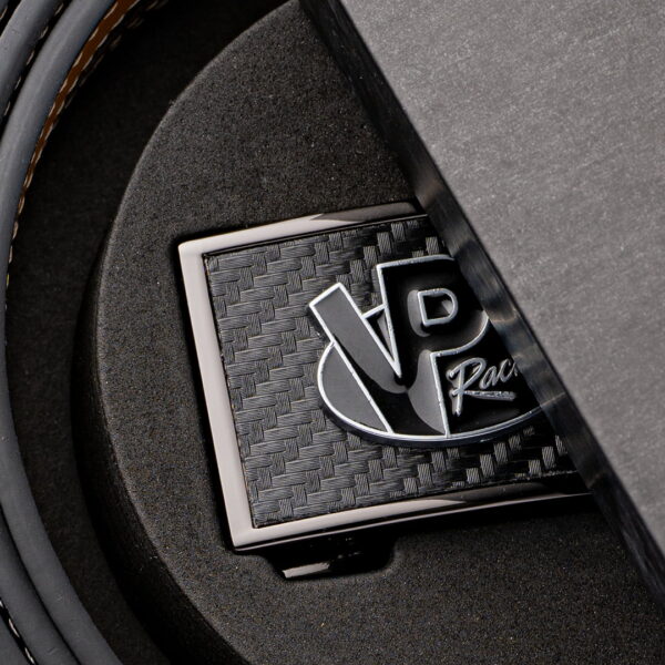 Close-up partial view of the raised VP Racing brushed metal belt buckle with leather belt inside the box